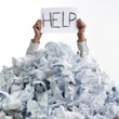 A business man drowning in paper holding a card saying HELP